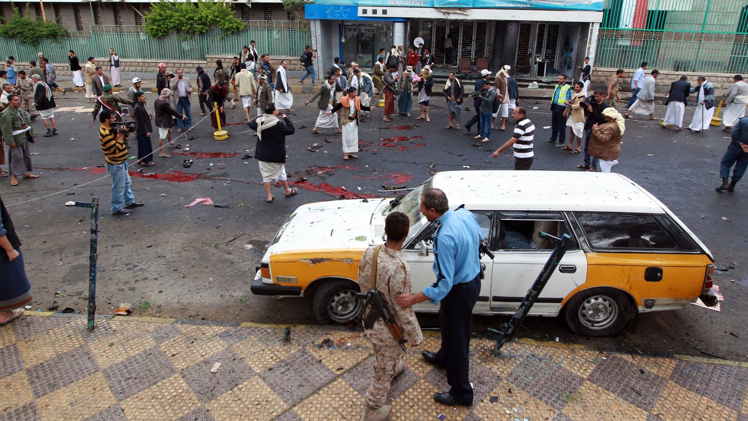  Yemeni security forces and Shiite Huthi militiamen stand next to pools of blood on the ground after a powerful suicide bombing.