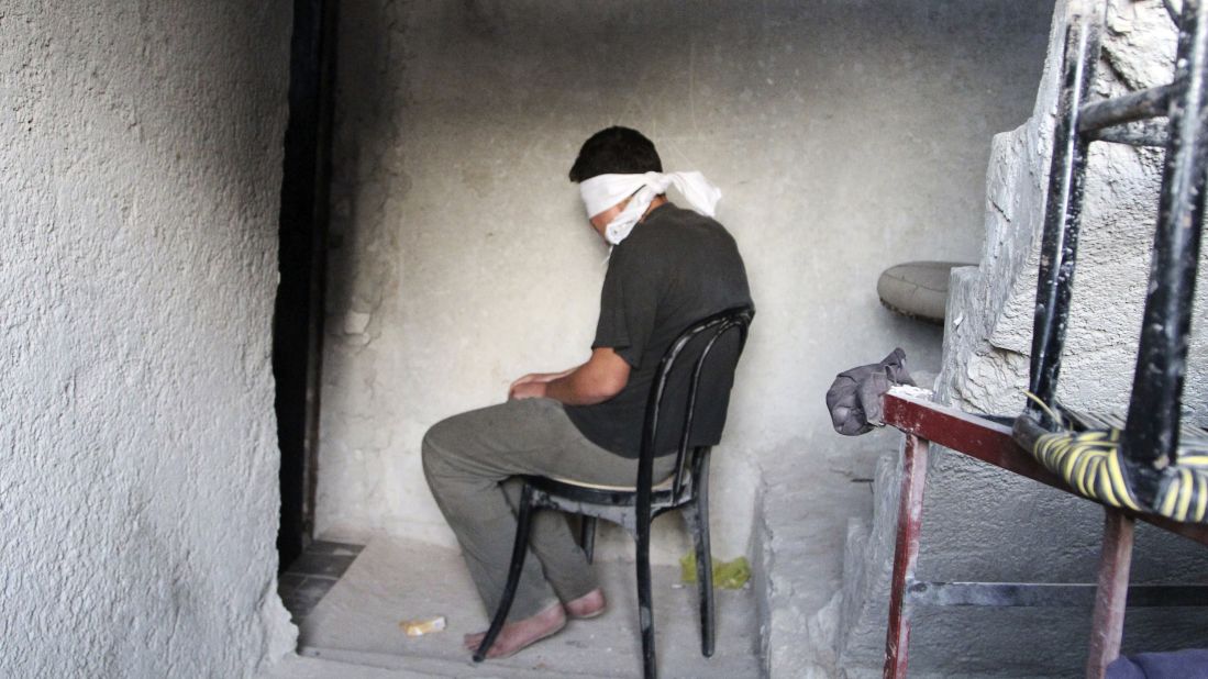 A blindfolded man suspected of passing military information to the Syrian government waits to be interrogated by Free Syrian Army fighters Monday, October 6, in Aleppo.