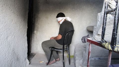A blindfolded man suspected of passing military information to the Syrian government waits to be interrogated by Free Syrian Army fighters Monday, October 6, in Aleppo.