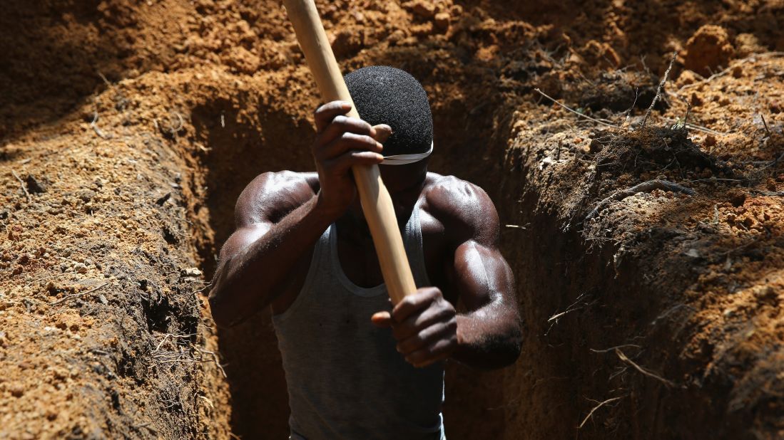 A man digs a grave on October 7, 2014, outside an Ebola treatment center near Gbarnga, Liberia. 