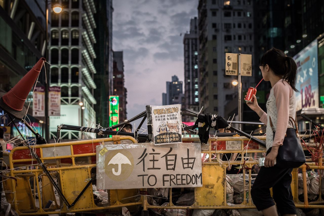 A woman drinks a soda as she walks past a barricade erected by pro-democracy demonstrators in Hong Kong on October 9.