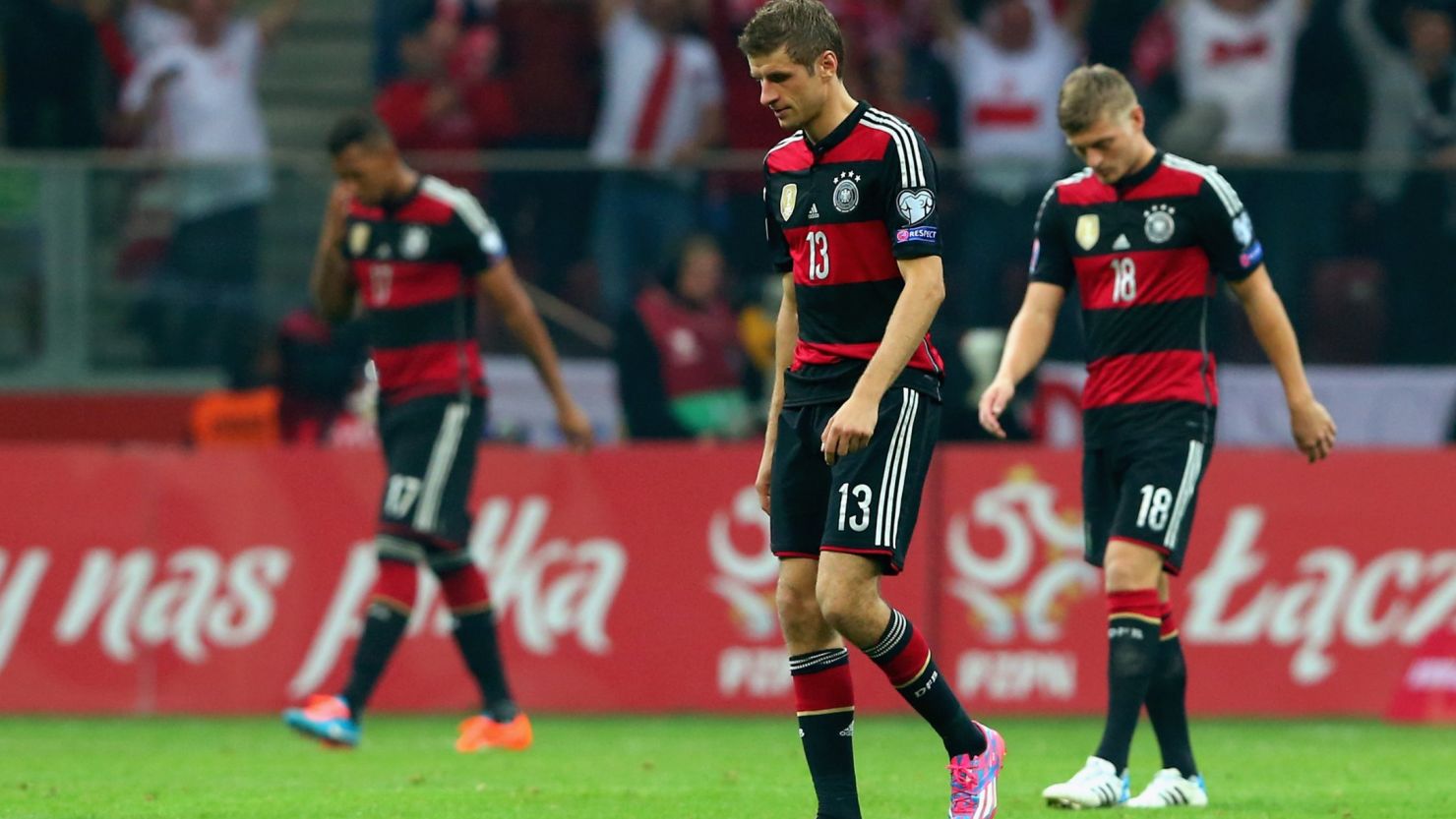 Thomas Muller (center) and Toni Kroos of Germany trudge off the pitch after being defeated by Poland in Warsaw.
