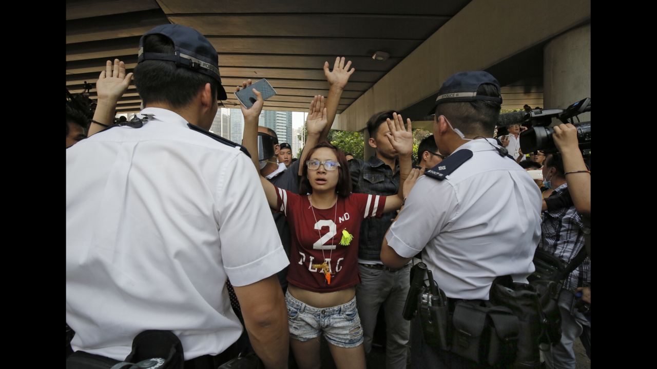Protesters raise their hands behind police officers after people tried to remove the metal barricades that protesters set up to block off main roads near the city's financial district on October 13. 