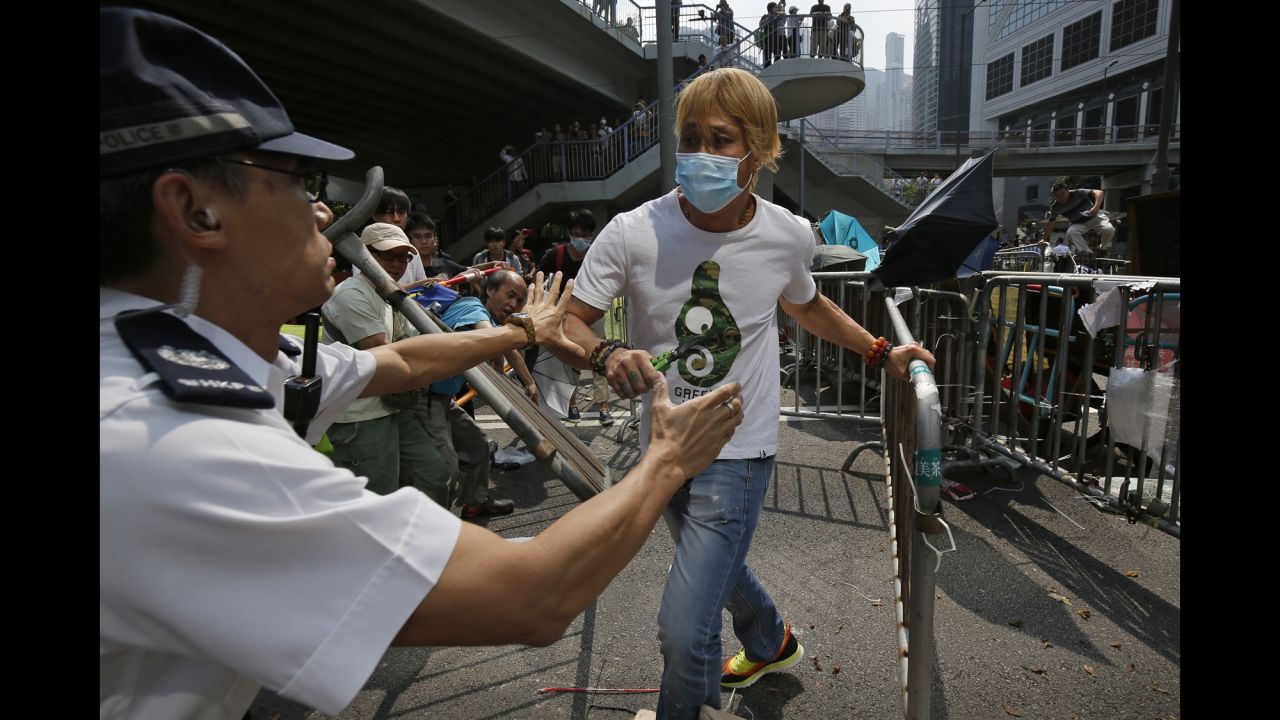 A police officer tries to stop a man from removing metal barricades set up by protesters on October 13.