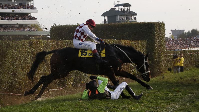 Josef Vana, aboard Tiumen, jumps over fellow jockey Josef Bartos after Bartos fell off his horse during the Velka Pardubicka Steeplechase in Pardubice, Czech Republic, on Sunday, October 12. The Taxis Fence, seen here, is the world's largest steeplechase fence.