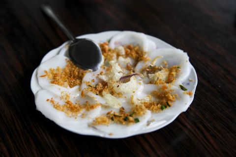 Bourdain eats bánh bèo, a steamed rice cake with crumbled fried shrimp, fried shallots and pork cracklings.