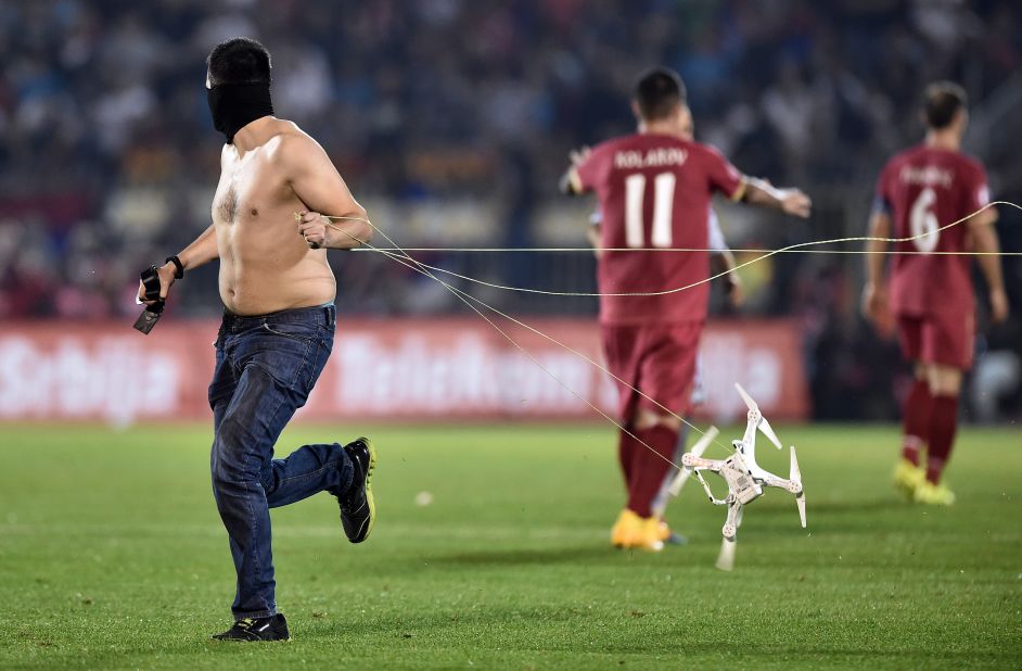 A fan drags the drone behind him after invading the pitch.