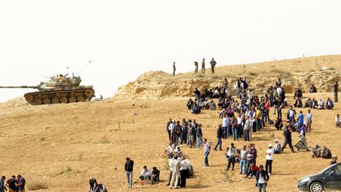 Kurdish people and Turkish soldiers watch fighting in the Syrian town of Kobani from a hilltop near the Turkish-Syrian border in this file photo.
