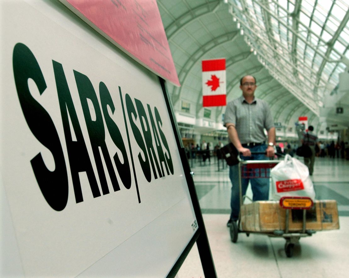 A passenger passes a SARS information board at Pearson airport in Toronto in May 2003. 