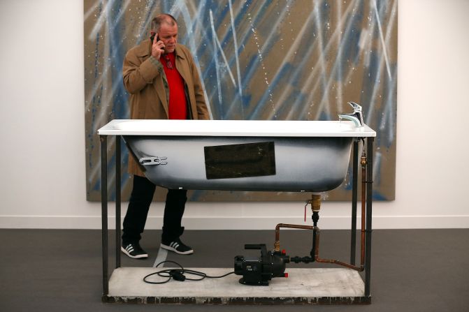 A visitor inspects a disembodied bath, better known as a sculpture by Oscar Tuazon titled "A Fountain".