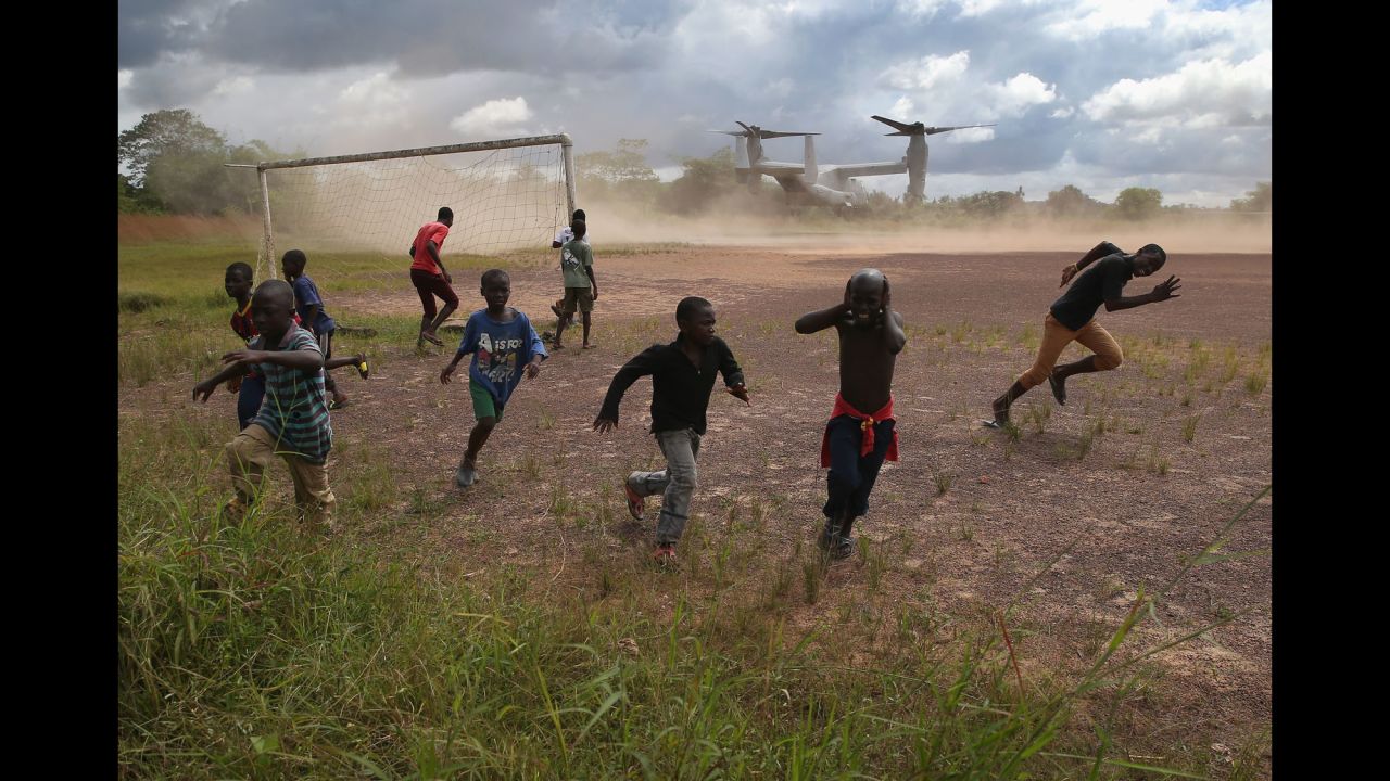 Boys run from blowing dust as a U.S. military aircraft leaves the construction site of an Ebola treatment center in Tubmanburg, Liberia, on October 15, 2014.