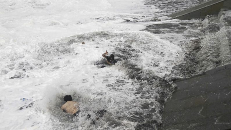 A man, left, jumps into water off the coast of Gopalpur, India, to rescue a woman who fell in because of strong tidal waves caused by <a href="http://www.cnn.com/2014/10/12/world/asia/india-cyclone/index.html">Cyclone Hudhud</a> on Sunday, October 12.