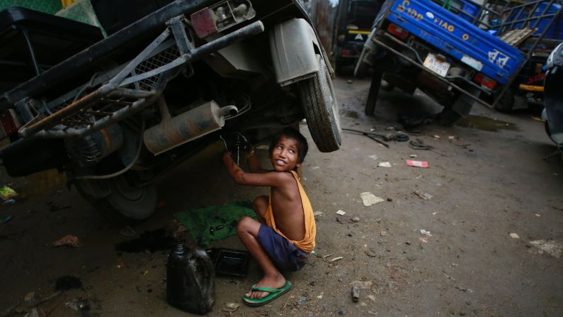 Biswa Gurung, a 7-year-old boy in Gauhati, India, talks to a colleague as he works at an automobile workshop on Sunday, October 12. Despite the country's rapid economic growth, child labor remains widespread in India.
