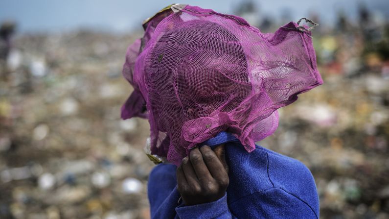 A boy covers his face Tuesday, October 14, as others sift through garbage at a dump in Maputo, Mozambique.