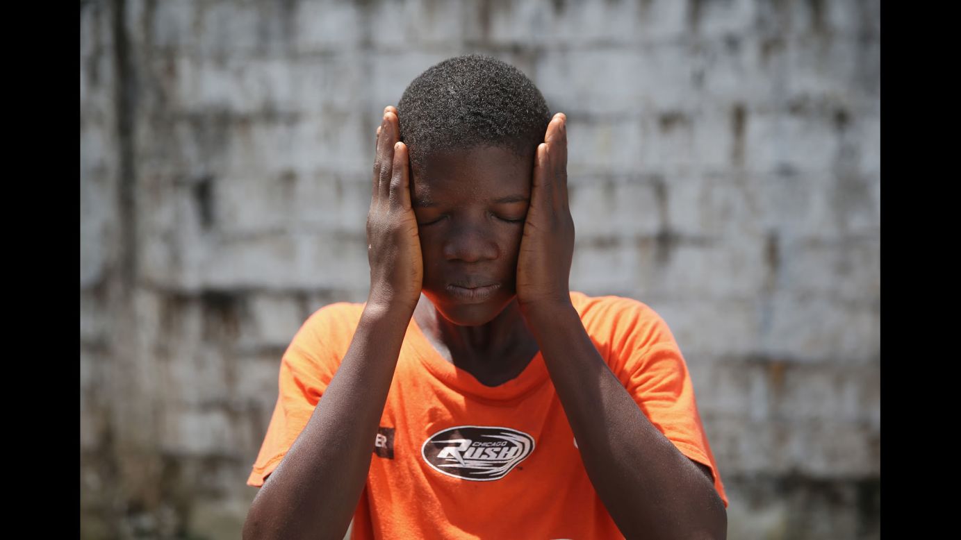 Ebola survivor Jeremra Cooper, 16, wipes his face from the heat while in the low-risk section of the Doctors Without Borders (MSF) Ebola treatment center in Paynesville, Liberia, on Thursday, October 16. The eighth grade student said he lost six family members to the Ebola epidemic before coming down sick with the disease himself and being sent to the MSF center, where he recovered after one month. 