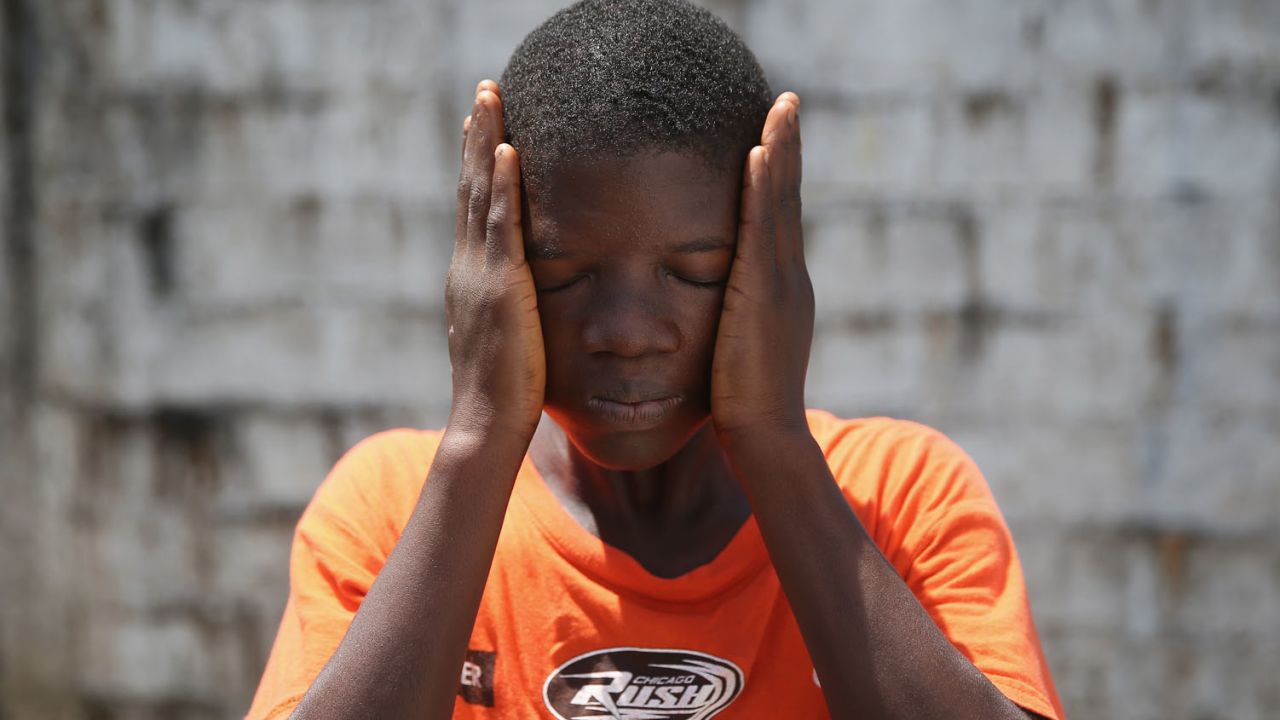 Ebola survivor Jeremra Cooper, 16, wipes his face from the heat while in the low-risk section of the Doctors Without Borders (MSF) Ebola treatment center in Paynesville, Liberia, on Thursday, October 16. The 8th grade student said he lost six family members to the Ebola epidemic before coming down sick with the disease himself and being sent to the MSF center, where he recovered after one month. 