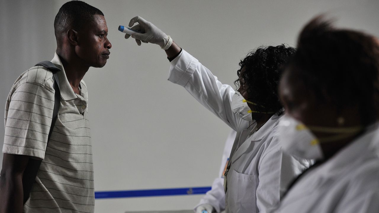 Kenyan health officials take passengers' temperatures as they arrive at the airport in Nairobi.