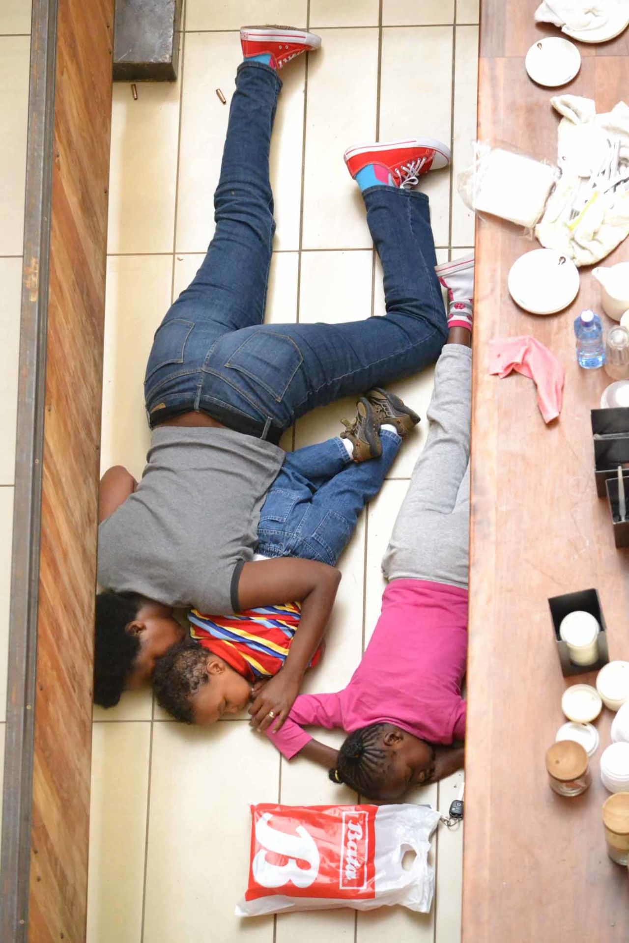 In this photograph from Mathenge, a mother and her two children lie face down on the floor pretending to be dead during the nightmare attacks at Nairobi's upscale shopping mall last year.