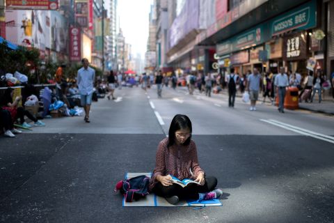 A woman reads on a road barricaded by pro-democracy protesters on October 19.