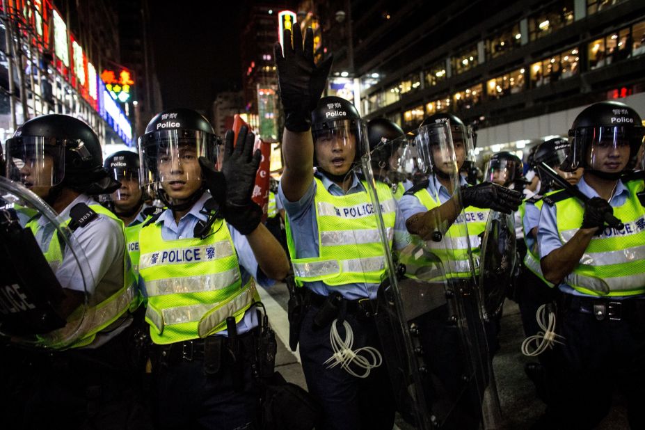 Police officers yell at pro-democracy protesters as they push forward in an attempt to clear a street on Saturday, October 18.