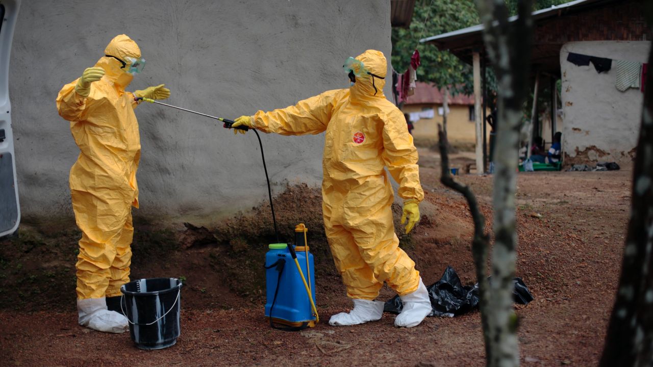 FILE - In this Sept. 30, 2014, file photo, Gordon Kamara, left, is sprayed by Konah Deno after they loaded six patients suspected to have been infected by the Ebola virus into their ambulance in the village of Freeman Reserve, about 30 miles north of Monrovia, Liberia. *AP Photo/Jerome Delay, File)