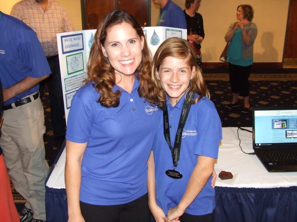 Tomasello and her daughter Catie stand in front of her display at the 2014<a href="index.php?page=&url=http%3A%2F%2Fwww.exploravision.org%2F" target="_blank" target="_blank"> Exploravision awards </a>weekend. "Catie and her teammates have blown me away with their creativity and desire to use science and technology to help others, and to make the world a better place. Their projects have included an innovative medical device for people with allergies, clean energy for homes and communities, and environmentally friendly methods to desalinate water." <br /> <br /><br />"A 'proud mom' moment came this summer when Catie explained her team's winning idea, the WateRenew, to a room of over 200 at the National Press Club, packed with corporate officials from Toshiba, including the CEO, educators, scientists, and members of the press. The scientist who created the Wave Wing prototype offered Catie and her teammates each a job upon college graduation with a degree in a science field. Catie is in sixth grade now, but she already has a job waiting for her!" 