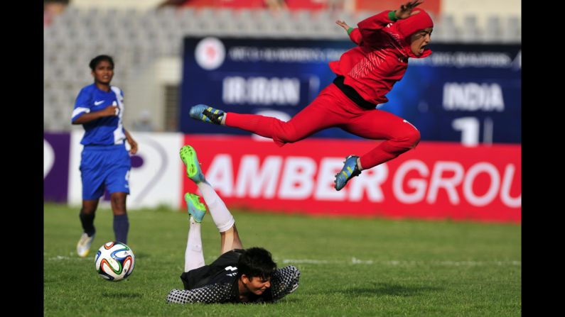 Iran's Fatemeh Ghasemi leaps over a goalkeeper from India during a AFC under-16 qualifying match Friday, October 17, in Dhaka, Bangladesh. 