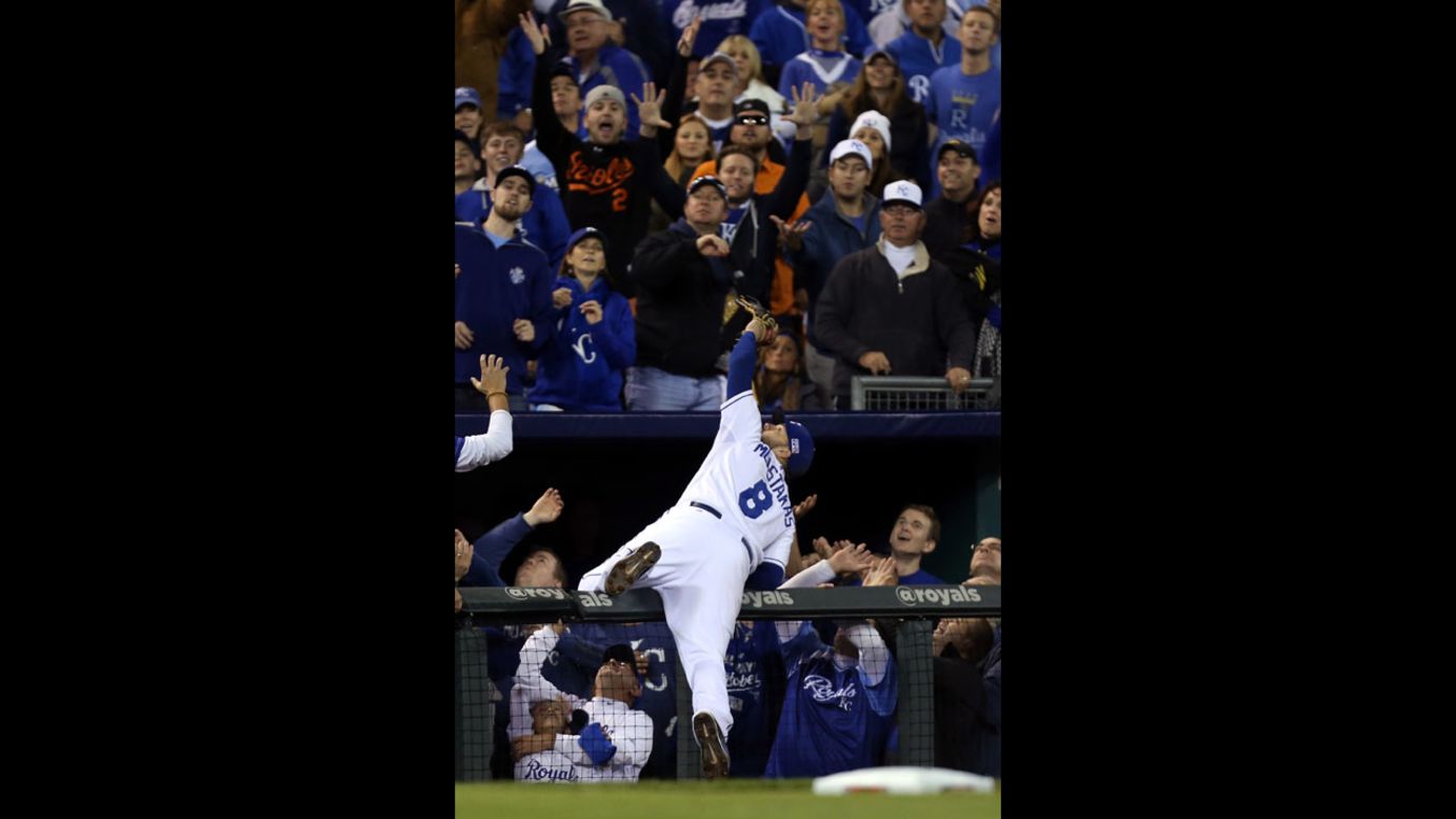 Kansas City Royals third baseman Mike Moustakas dives into spectators as he catches a foul ball Tuesday, October 14, in Game 3 of the American League Championship Series.