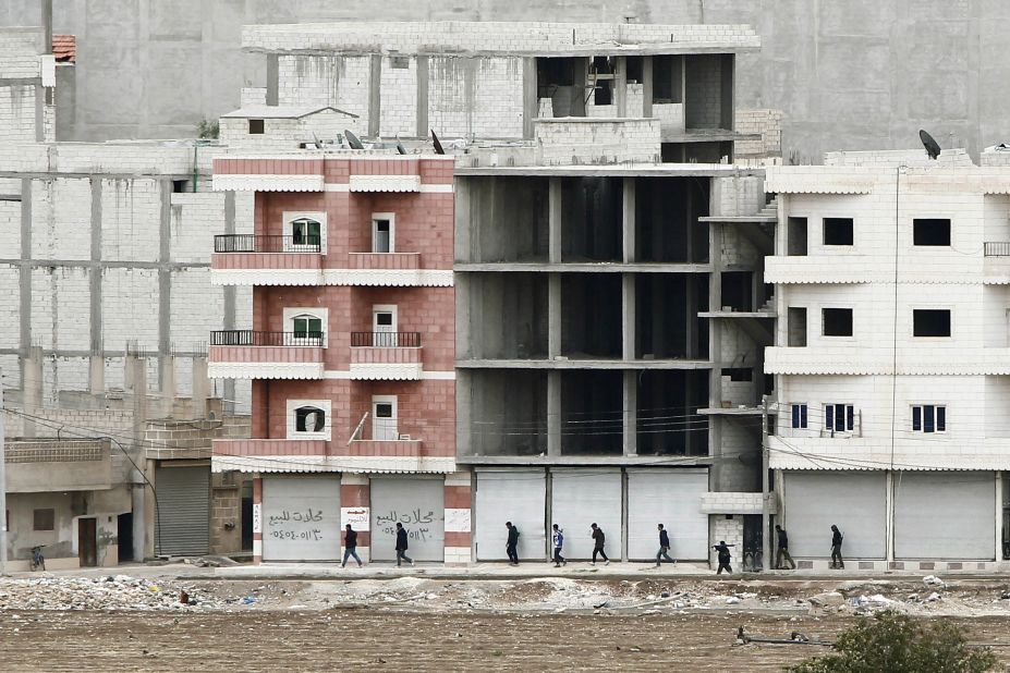 Kurdish fighters walk to positions as they combat ISIS forces in Kobani on Sunday, October 19.