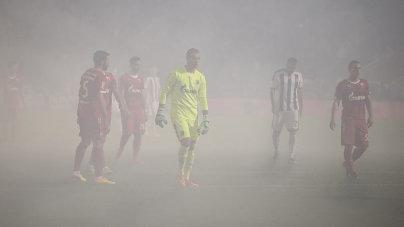 Smoke surrounds soccer players from Partizan and Red Star after fans lit flares during the rivalry match Saturday, October 18, in Belgrade, Serbia. Play was held up twice so that smoke could clear. After the smoke cleared, Partizan would go on to win 1-0.