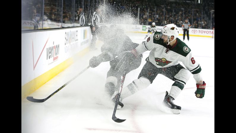 Los Angeles Kings captain Dustin Brown, left, gets lost in a cloud of ice spray as he battles Minnesota's Marco Scandella for the puck Sunday, October 19, in Los Angeles.
