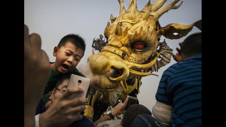 A boy sits on his father's shoulders as they take a selfie in front of a large mechanical dragon Saturday, October 18, at the National Stadium in Beijing. The dragon, which sprays water, was part of an event celebrating 50 years of diplomatic relations between China and France.