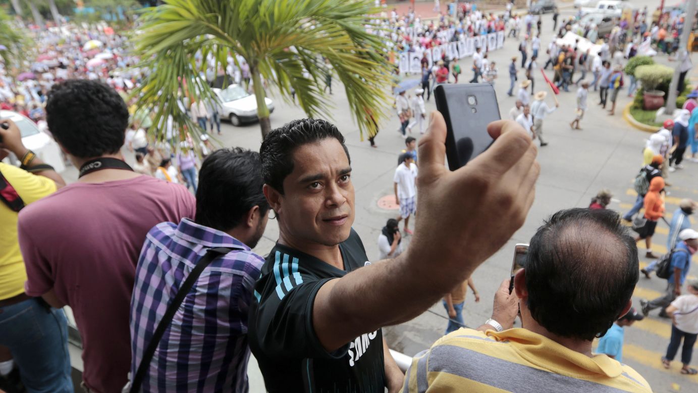 A tourist takes a selfie during a protest march in Acapulco, Mexico, on Friday, October 17. Thousands of protesters marched to demand the safe return of 43 students <a href="http://www.cnn.com/2014/10/06/world/americas/mexico-iguala-mass-graves-missing-students/index.html">who went missing</a> last month.