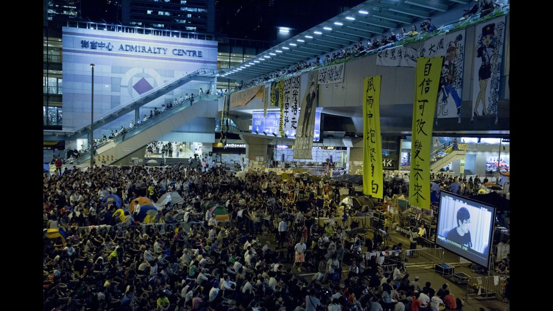 Pro-democracy protesters at an occupied area outside the government headquarters in Hong Kong watch a live broadcast of talks between Hong Kong government officials and protesters on Tuesday, October 21.