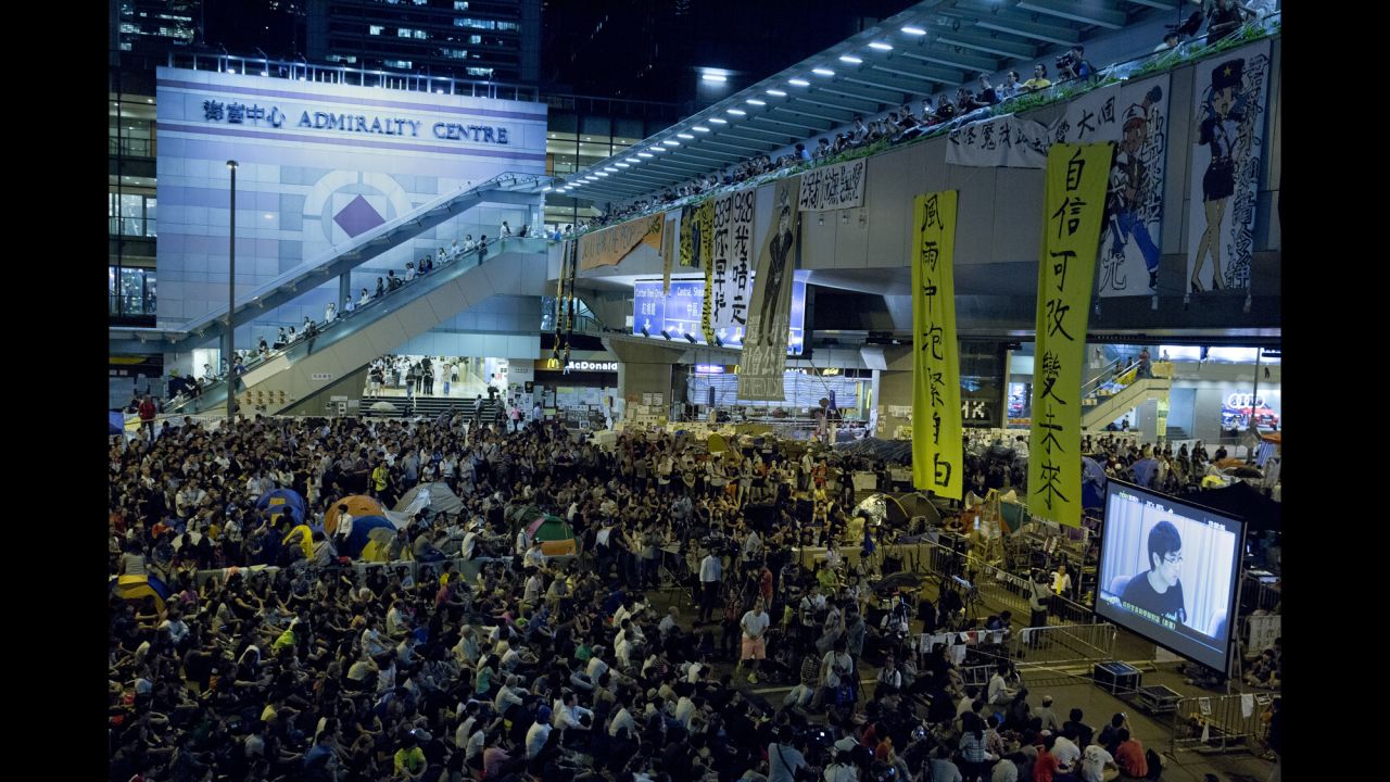 Pro-democracy protesters at an occupied area outside the government headquarters in Hong Kong watch a live broadcast of talks between Hong Kong government officials and protesters on Tuesday, October 21.