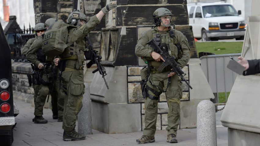 A Royal Canadian Mounted Police intervention team walks past a gate on Parliament hill.