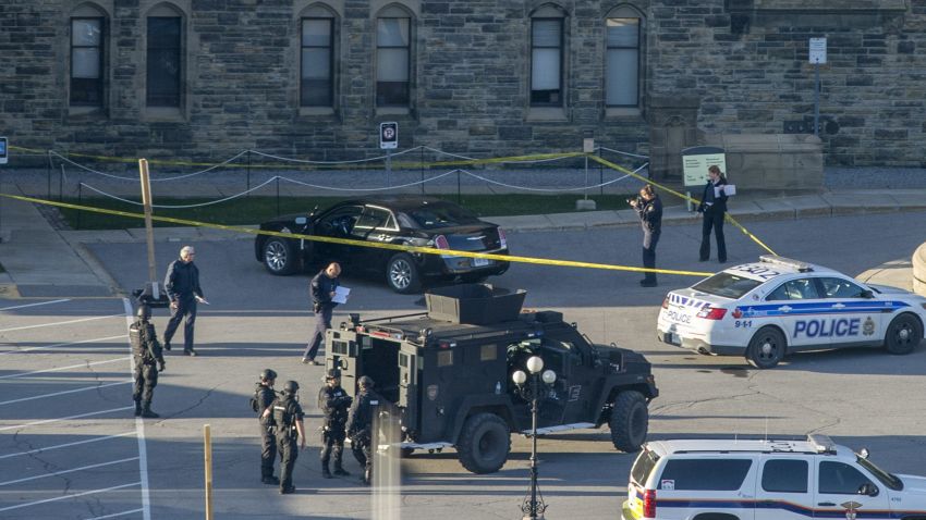 A police officer takes a photo of a vehicle, top, inside police tape outside Center Block on Parliament Hill in Ottawa, Ontario, Wednesday, Oct. 22, 2014. A gunman with a scarf over his face shot to death a Canadian soldier standing guard at the nation's war memorial Wednesday, then stormed Parliament in a hail of gunfire before he was killed by the usually ceremonial sergeant-at-arms, authorities and witnesses said. (AP Photo/The Canadian Press, Justin Tang/The Canadian Press/AP)
