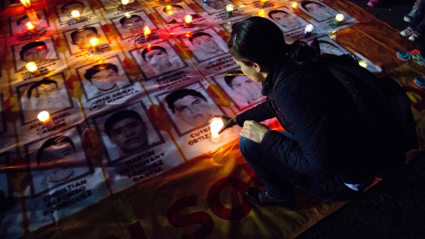 A woman places a candle on photos of the missing students during a protest against the disappearance of 43 students from the Isidro Burgos rural teachers college, in Mexico City, Wednesday, Oct. 22, 2014. Tens of thousands marched in Mexico City's main avenue demanding the return of the missing students. The Mexican government says it still does not know what happened to the young people after they were rounded up by local police in Iguala, a town in southern Mexico, and allegedly handed over to gunmen from a drug cartel Sept. 26, even though authorities have arrested 50 people allegedly involved. They include police officers and alleged members of the Guerreros Unidos cartel. (AP Photo/Eduardo Verdugo)