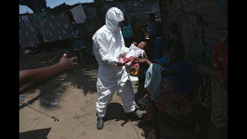 A mother hands her son to a health worker in Monrovia, Liberia, on Friday, October 17. The baby, his mother and his grandmother were all taken to an Ebola holding center after they were all found to have a fever. Health officials say <a href="http://www.cnn.com/2014/04/04/world/gallery/ebola-in-west-africa/index.html">the Ebola outbreak in West Africa</a> is the deadliest ever. More than 4,800 people have died there, according to the World Health Organization.