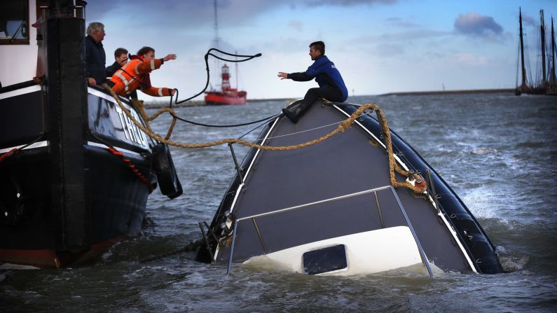 Rescuers try to save a sinking ship in the Dutch harbor of Harlingen on Wednesday, October 22. The remnants of Hurricane Gonzalo affected many parts of Europe.
