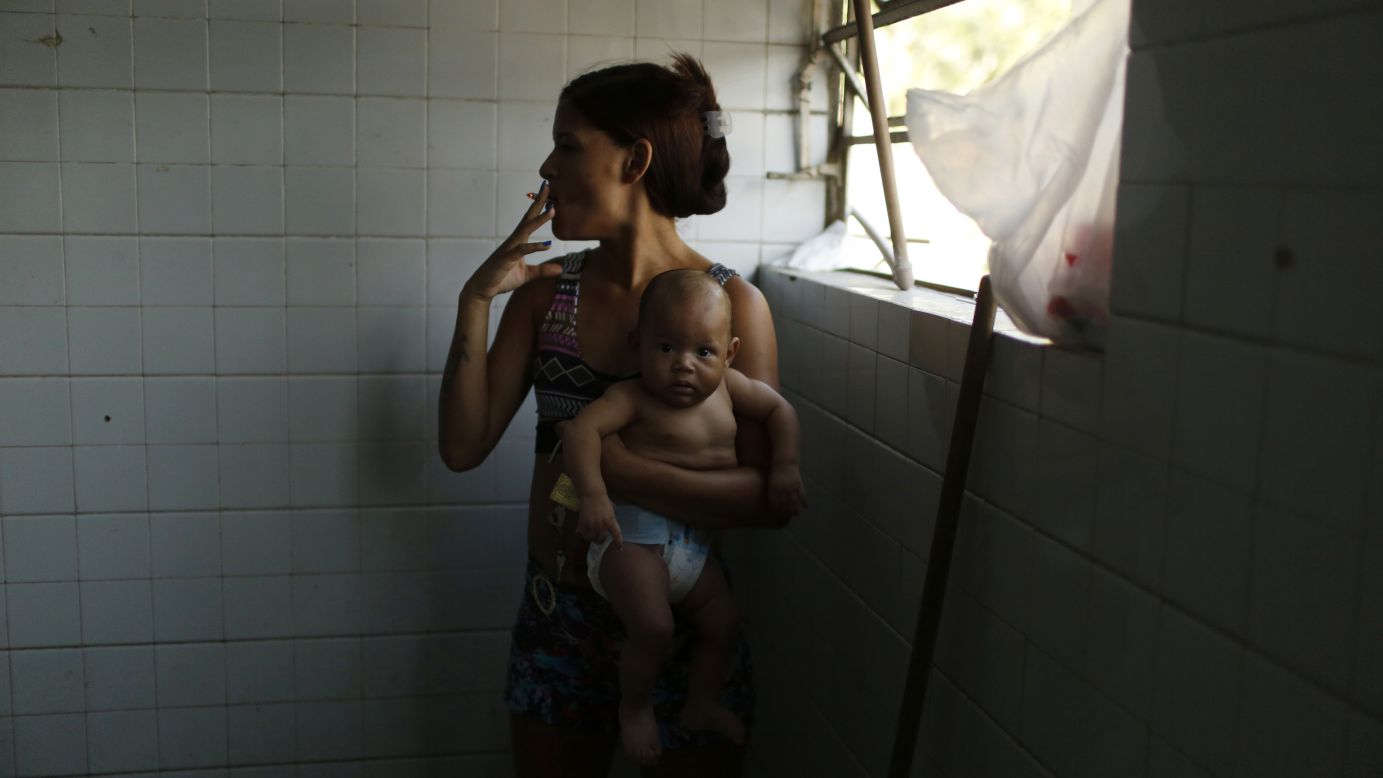 A woman holds her baby and smokes a cigarette Friday, October 17, as she waits for a washing machine inside the bathroom of an abandoned factory in Rio de Janeiro. For the past seven months, 1,800 families have been living inside the factory.