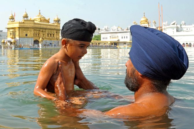 An Indian Sikh devotee holds a child as they take a dip in the holy sarover (water tank) during Bandi Chhor Divas at the Golden Temple in Amritsar.