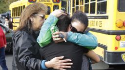 People embracein fron of school busses as they are reunited.