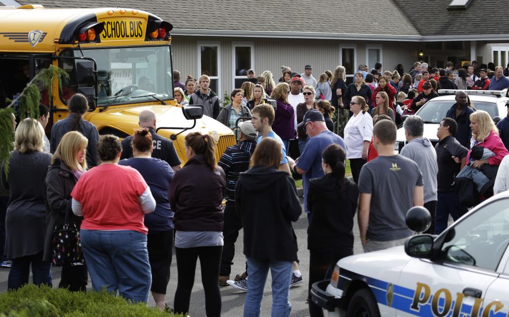 Parents crowd around buses as students arrive at the church. 