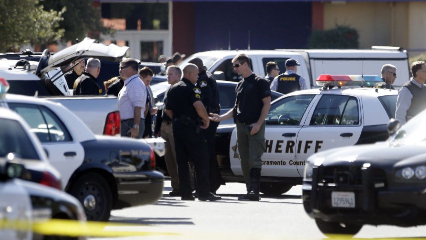 Law enforcement officers gather at the site where a Sacramento County Sheriff's deputy was shot by an assailant who then carjacked two vehicles prompting a manhunt in Sacramento, Calif., Friday, Oct. 24, 2014. The deputy was taken to a hospital but his condition is not immediately known.(AP Photo/Rich Pedroncelli)