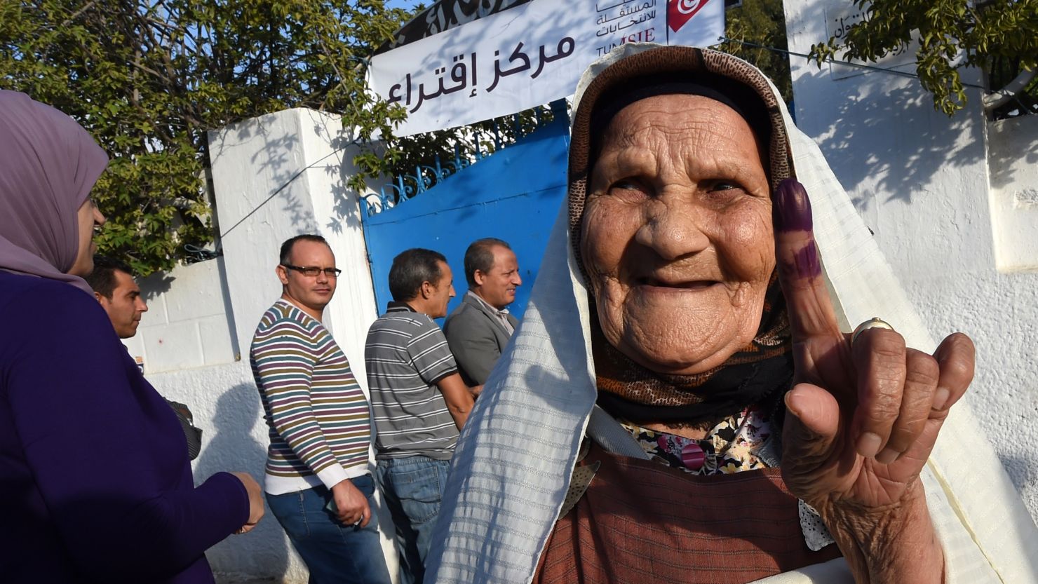 A Tunisian woman shows her ink-stained finger as she leaves a polling station on October 26, 2014.