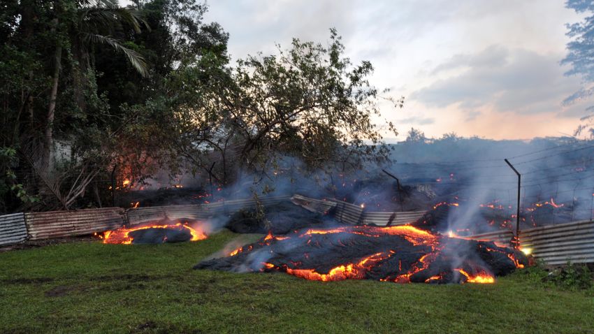 The June 27th lava flow burns vegetation as it approaches a property boundary above P hoa early on the morning of Tuesday, October 28, 2014.
Lava pushed through a fence marking a property boundary above P hoa early on Tuesday morning. By dawn on Tuesday morning, lava had crossed into two privately owned properties above P hoa. Note the inflated flow behind the fence, which is chest-high. We are grateful to the owners of the property for allowing us access and permission to work on their land and post these photos.