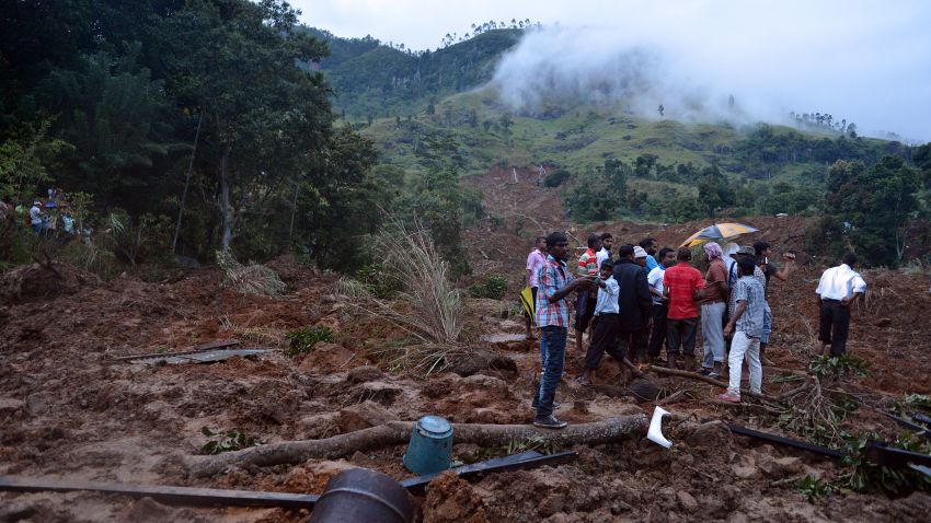 :Sri Lankan residents stand at the site of a landslide caused by heavy monsoon rains in Koslanda village in central Sri Lanka on October 29, 2014. 