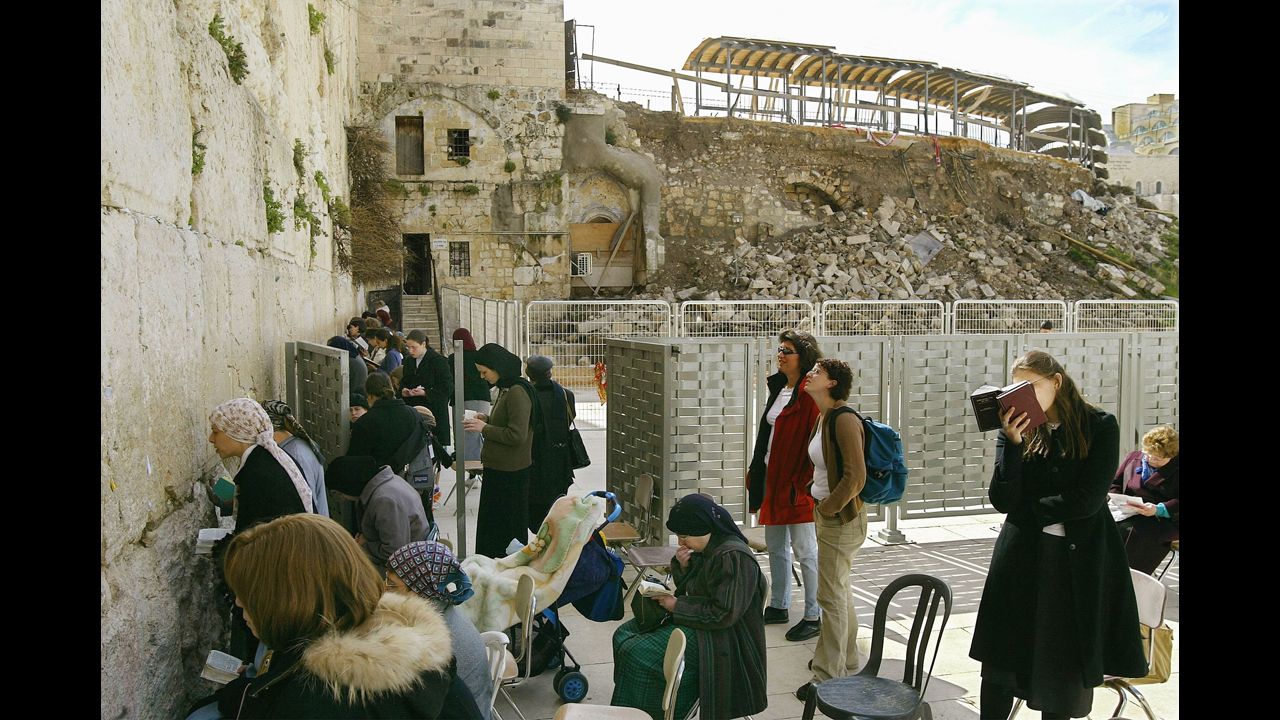 Jewish women pray behind a barrier at the Western Wall in February 2004, following a collapse of the wall into the prayer area.