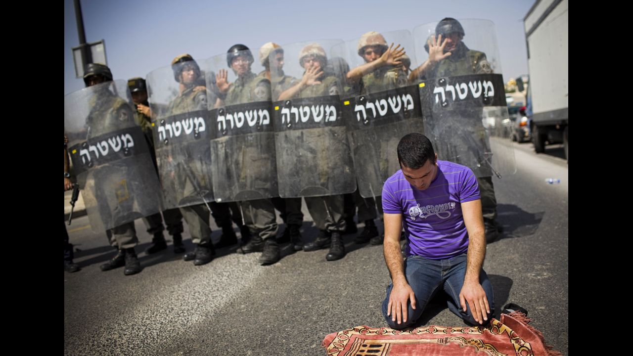 A Palestinian worshipper who was prevented from reaching the al-Aqsa Mosque prays outside Jerusalem's Old City while Israeli forces stand guard in March 2010. Police had temporarily limited access.
